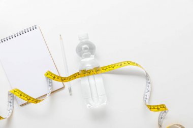 top view of water in bottle, measuring tape, blank notebook with pencil on white background  clipart