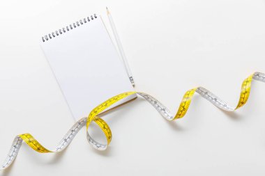 Ölçüm bandı üst görünümü, beyaz arka plan üzerinde kalem ile boş Notebook 