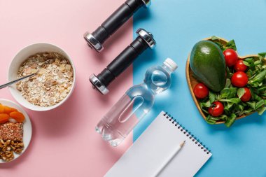 mavi ve pembe arka planda diyet gıda yakın su, dambıl ve boş Notebook ile şişe üst görünümü