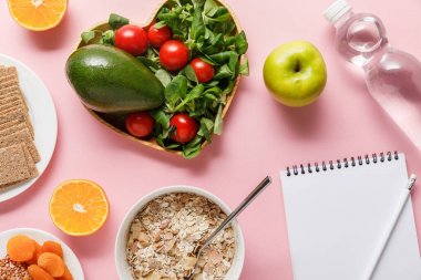 taze diyet gıda üst görünümü, pembe arka plan üzerinde kalem ve su ile boş Notebook
