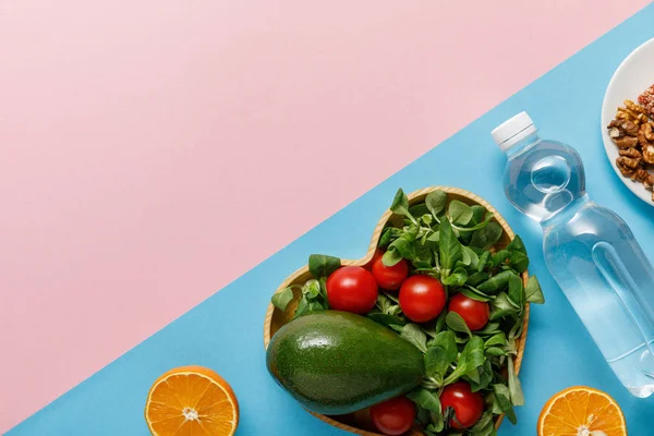 ピンクとブルーの背景に野菜サラダ オレンジ 水とナッツと平らなレイ — ストック写真