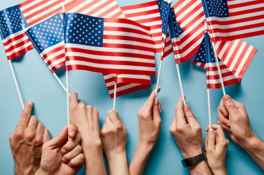 cropped view of people holding american flags on sticks on blue background  clipart