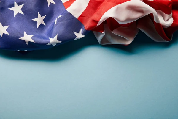 close up view of crumpled american flag on blue background with copy space