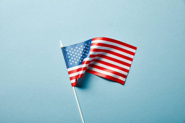 top view of american flag on stick on blue background 