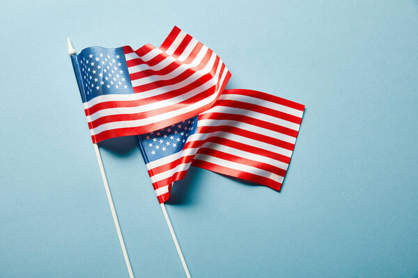 top view of american flags on sticks on blue background