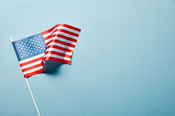 top view of usa flag on stick on blue background with copy space