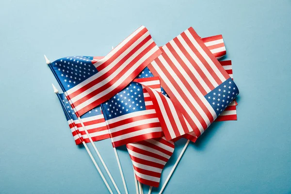 top view of american flags stacked on blue background