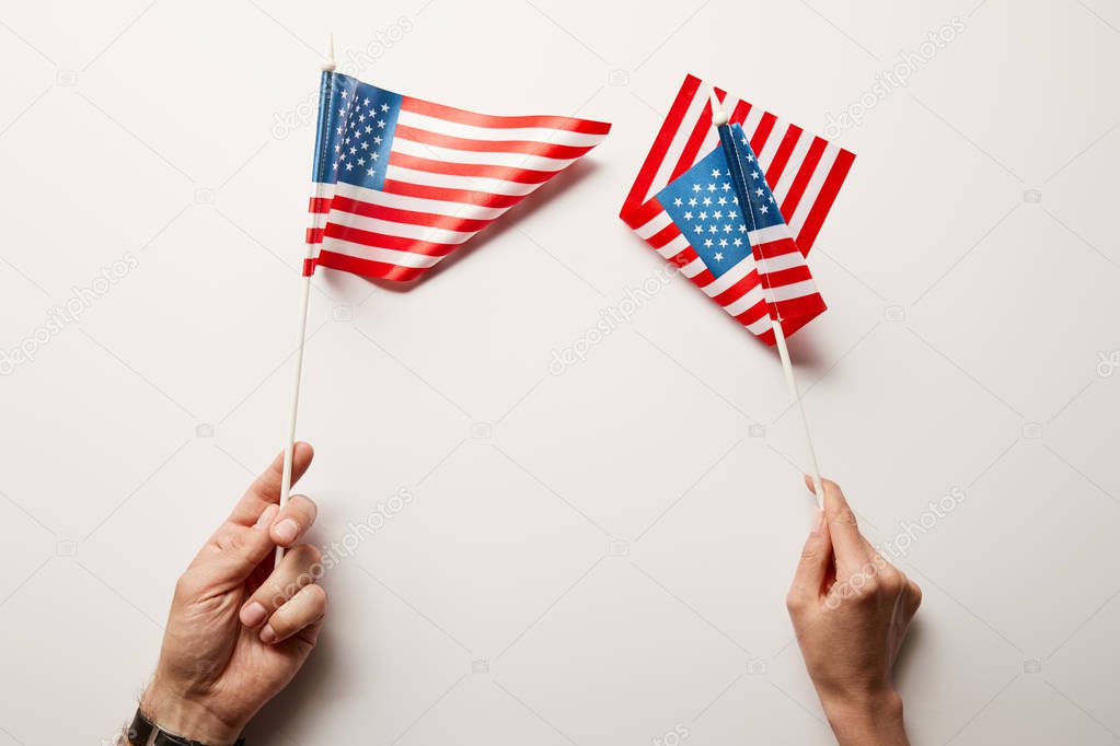 cropped view of woman and man holding american flags on white background 