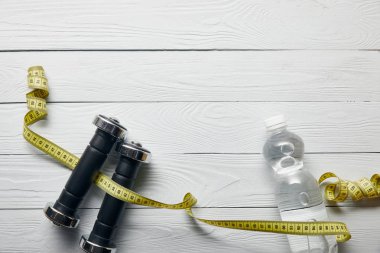 su ile şişe üst görünümü, kopya alanı ile ahşap beyaz arka plan üzerinde bant ve dambıl ölçme