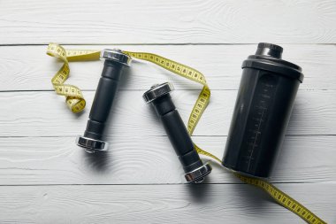 siyah shaker fincan üst görünümü, ahşap beyaz arka plan üzerinde sarı ölçüm bandı ve halter 