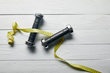 kopya alanı ile ahşap beyaz arka plan üzerinde bant ve dambıl ölçme üst görünümü