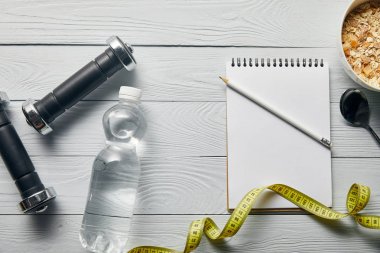 dambılüst görünümü, şişede su, ahşap beyaz arka plan üzerinde kase içinde kopya alanı, kalem, kaşık ve kahvaltılık gevrek ile bant ve boş defter ölçme 