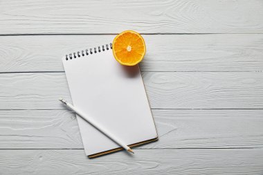 kopya alanı ile ahşap beyaz arka plan turuncu yarım, boş defter ve kalem üst görünümü
