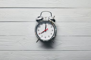 ahşap beyaz arka plan üzerinde gümüş çalar saat üst görünümü 