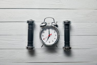 düz ahşap beyaz arka plan üzerinde gümüş çalar saat ve siyah halter ile yatıyordu 