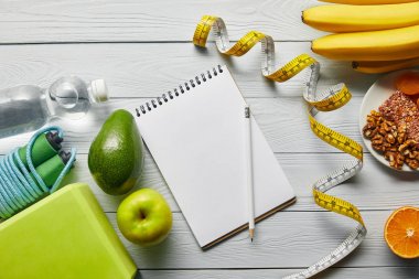ahşap beyaz arka plan üzerinde bant, dizüstü bilgisayar ve spor ekipmanları ölçme yakın diyet gıda üst görünümü