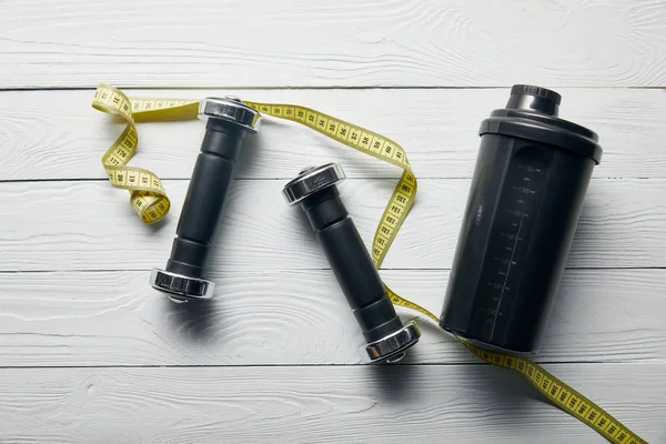 Top View Black Shaker Cup Yellow Measuring Tape Dumbbells Wooden — Stock Photo, Image