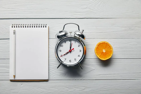 Flat Lay Silver Alarm Clock Empty Notebook Pencil Orange Half — Stock Photo, Image