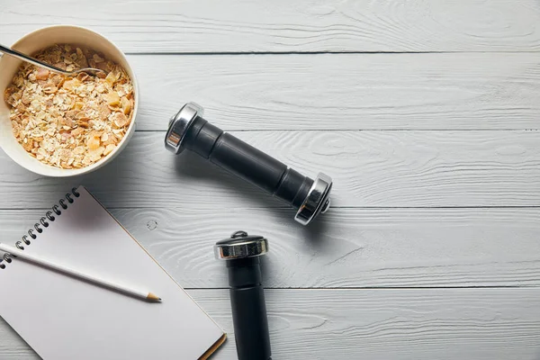 Top View Breakfast Cereal Bowl Dumbbells Notebook Pencil Wooden White — Stock Photo, Image