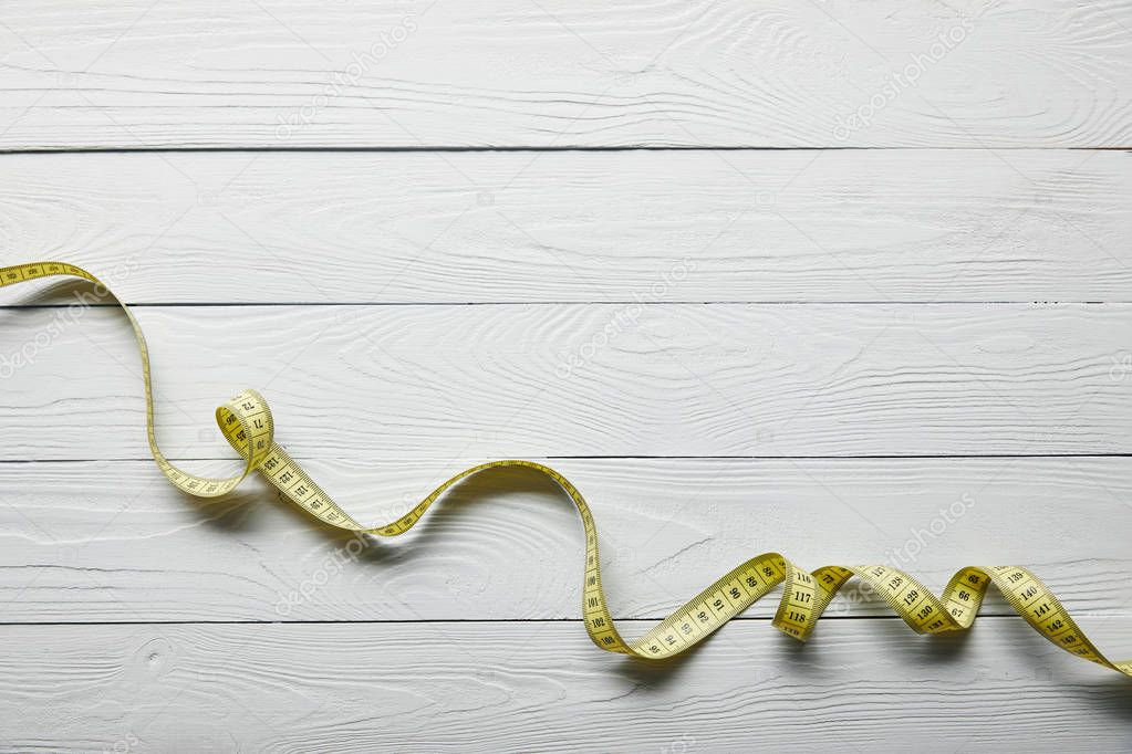 top view yellow measuring tape on wooden white background with copy space