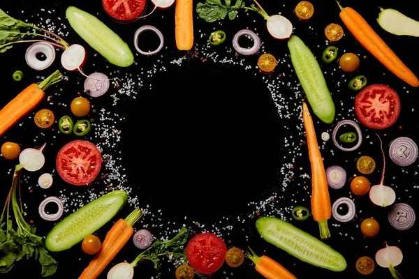 新鲜蔬菜片的顶部视图与盐与空的圆形框架隔离在黑色 — 图库照片