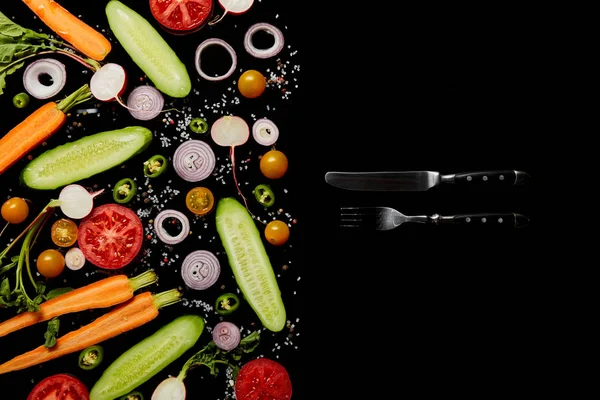 黒のコピースペースで孤立したナイフとフォークの近くに塩で新鮮な野菜スライスのトップビュー — ストック写真