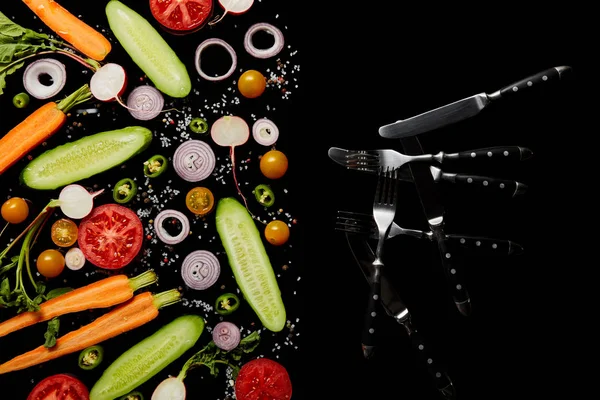 コピースペースで黒に分離されたナイフとフォークの近くに塩で新鮮な野菜スライスのトップビュー — ストック写真
