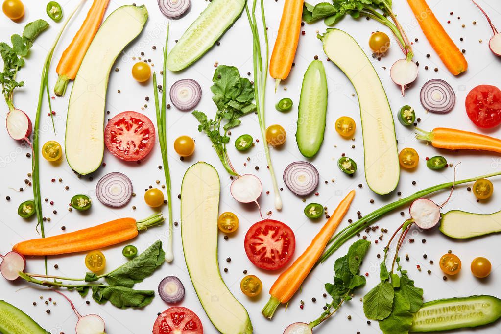 top view of fresh sliced vegetables and black pepper on white background