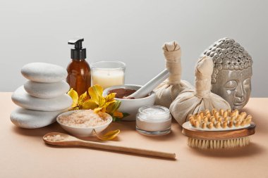 spa kozmetik, taşlar, masaj fırçası, mum, gri izole bej yüzeyinde Buda heykelcik