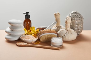 spa organik kozmetik, taşlar, masaj fırçası, mum, gri izole bej yüzeyinde Buda heykelcik