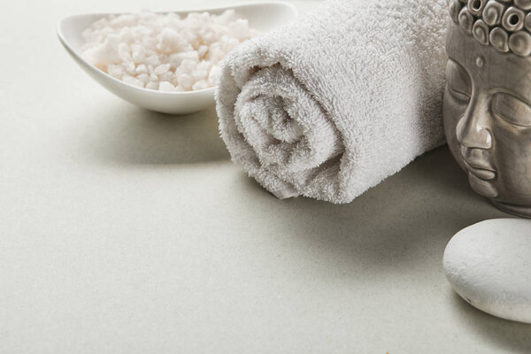 sea salt in bowl, cotton towel, stone and Buddha figurine on white background