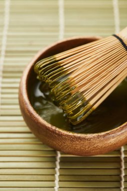masa mat üzerinde ahşap kase yeşil matcha tozu ve bambu çırpıcı seçici odak