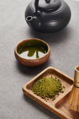 yeşil matcha tozu ve bambu çırpıcı siyah çaydanlık ve çay ile kase yakın ahşap tahta üzerinde