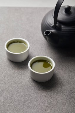 gri taş masa üzerinde matcha çay ile siyah çaydanlık ve beyaz bardak seçici odak