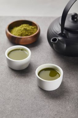 çay ve siyah çaydanlık ile bardak yakınında ahşap kase yeşil matcha tozu seçici odak