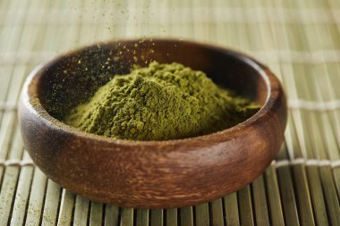bambu masa paspas ı üzerine tahta kaseye dökülen yeşil matcha tozu seçici odak