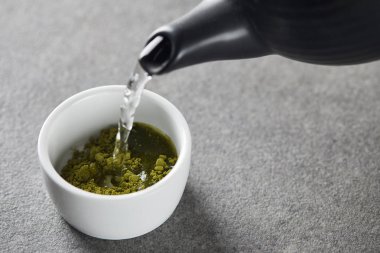 siyah çaydanlık yeşil matcha tozu ile beyaz fincan su dökme