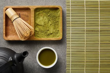 beyaz fincan, siyah çaydanlık ve masa mat yakın ahşap kase matcha tozu ile bambu çırpıcı üst görünümü