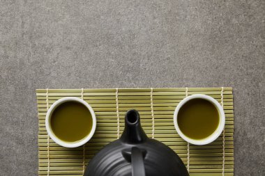 yeşil bambu masa paspas üzerinde matcha ve siyah çaydanlık ile beyaz bardak üst görünümü