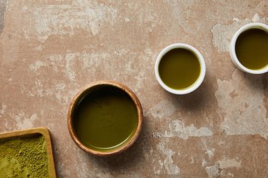matcha tozu üst görünümü, yaşlı yüzeyde yeşil çay ile kase ve bardak