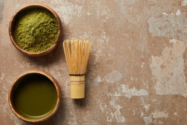 yaşlı yüzeyde bambu çırpıcı ile ahşap kase matcha çay ve yeşil toz üst görünümü