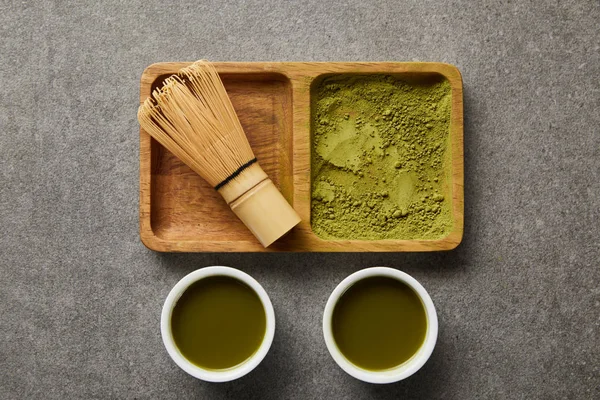 在木碗上用绿茶接近白杯的竹胡须和火柴粉的顶视图 — 图库照片