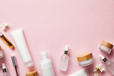 top view of cream tubes, cosmetic dispenser, empty jars and with hand cream, mascara bottles on pink  clipart