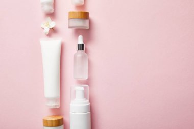 pembe üzerinde farklı kozmetik kaplar ve yasemin çiçek düz yatıyordu 