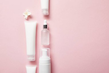 kozmetik cam şişe düz yatıyordu, krem ile krem tüpler, kozmetik dispenser ve pembe yasemin çiçek 