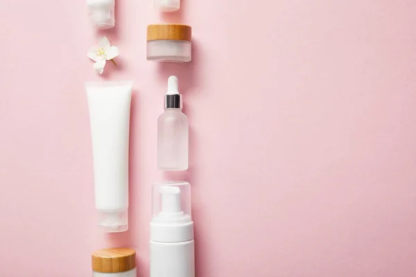 pembe üzerinde farklı kozmetik kaplar ve yasemin çiçek düz yatıyordu 