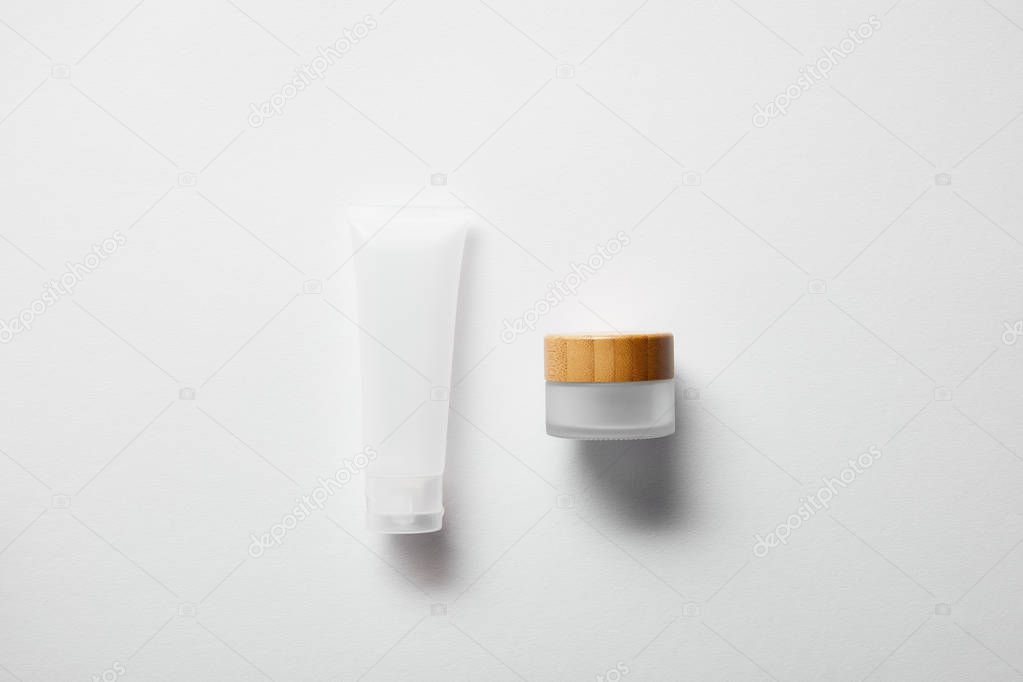 top view of jar with wooden cap and cream tube on white 