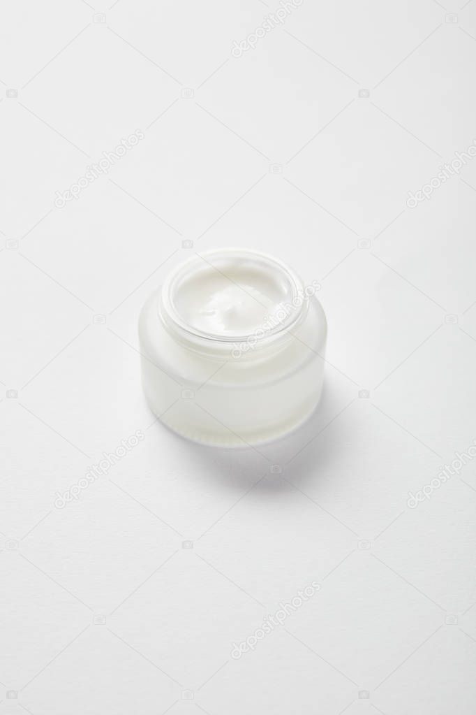 open glass jar with face cream on white 