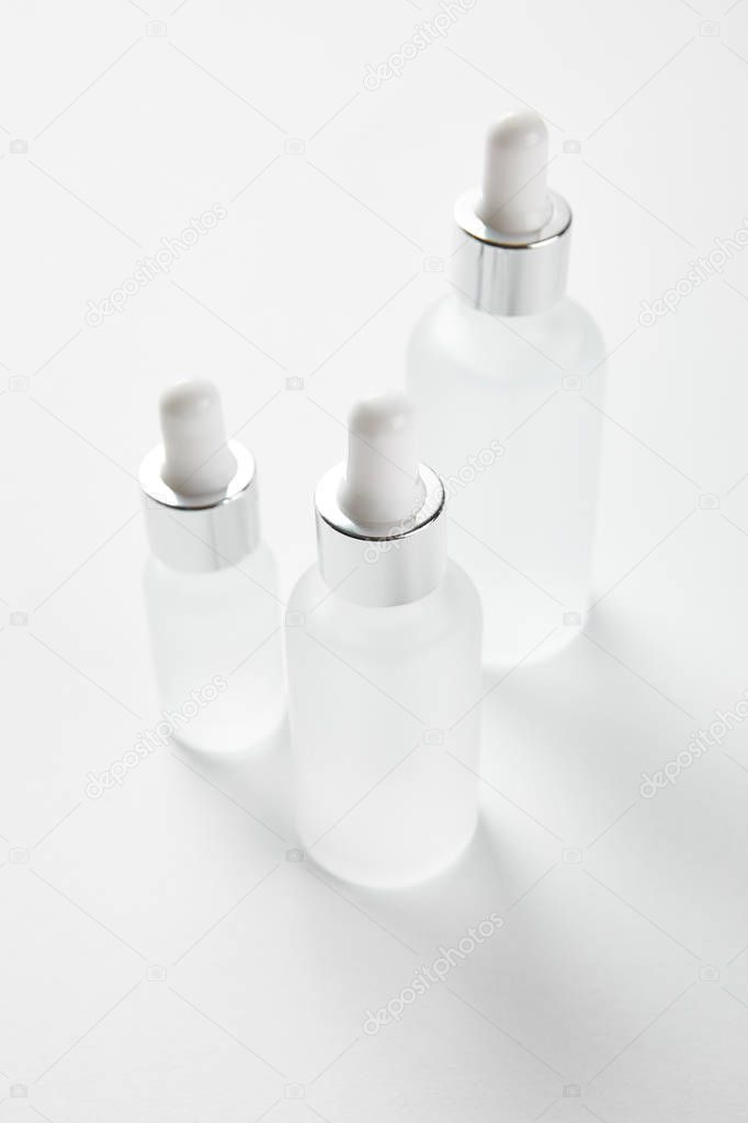 three glass bottles with serum on white 