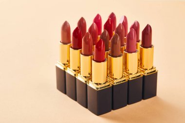 various red lipstick in tubes on beige  clipart